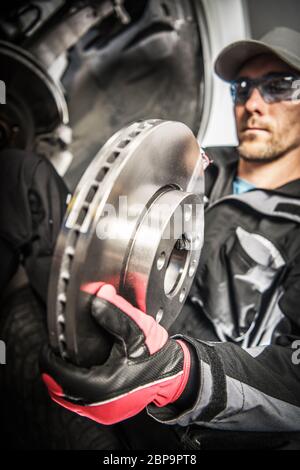 Technicien mâle caucasien travaillant à l'atelier de réparation automobile Remplacement du disque dans le système de freinage de voiture. Banque D'Images