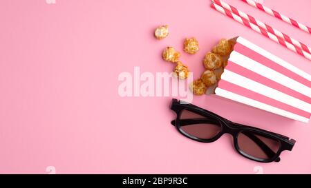 Concept de cinéma en ligne. Composition de plat avec pop-corn, verres 3d et pailles à boire sur fond rose. Concept de cinéma. Banque D'Images