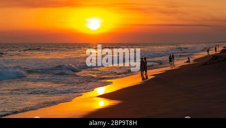 Coucher de soleil panoramique le long de la plage de sable volcanique de Monterrico avec les gens au bord de l'océan Pacifique, Guatemala. Banque D'Images