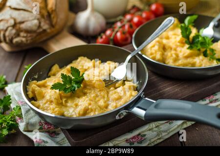 Oeufs brouillés aux fines herbes et du pain fait maison, sur deux poêles à frire Banque D'Images