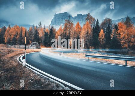 Voiture floue sur la route sinueuse dans les montagnes en soirée Banque D'Images