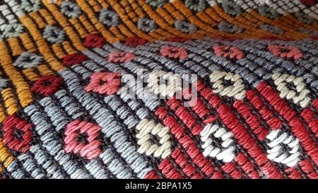 Plis de tissu tissé folk Craft avec motif losange texturé. Fond de tapis turc ornemental. Texture tissée de tapis colorés faits main. Banque D'Images