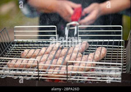Saucisses crues sur le gril. Saucisses fraîches au gril sur un barbecue. Banque D'Images