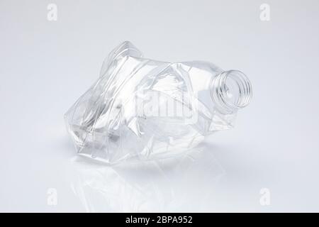 bouteille en plastique pellucide sans bouchon écrasé sur elle-même, isolée devant sur fond blanc Banque D'Images