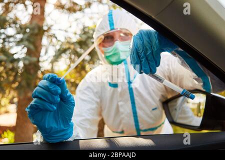 Confinement le scout du département de la Santé tient un écouvillon de gorge d'un test de coronavirus dans une station d'essai au volant Banque D'Images