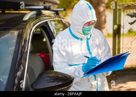 L'employé comme scout de confinement capture les visiteurs en voiture de la maison de soins infirmiers à la liste de visites pendant la pandémie du coronavirus Banque D'Images