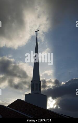 L'église Steeple est rétro-éclairée par les rayons du soleil couchant entouré de magnifiques nuages. Banque D'Images