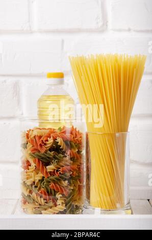 Pâtes crues en pots de verre et huile de cuisson sur le self de pantry Banque D'Images