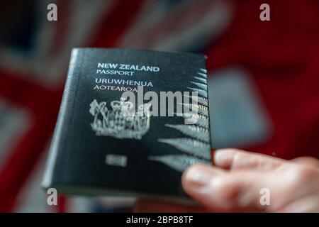 Passeport néo-zélandais en effet sélectif de foyer tenu avec drapeau de fond du pays Banque D'Images