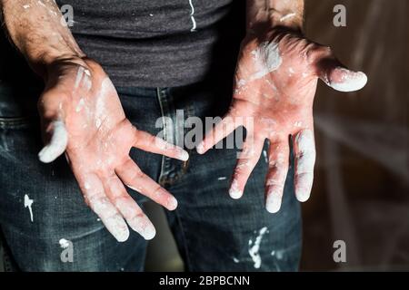 Artisan avec des particules de peinture blanche aux mains et aux vêtements après le travail de peinture rénovation sale travail de formation profession d'enseignement faites-le vous-même Banque D'Images