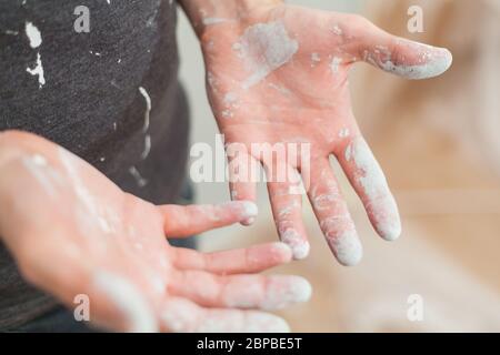 Artisan avec des particules de peinture blanche aux mains et aux vêtements après le travail de peinture rénovation sale travail de formation profession d'enseignement faites-le vous-même Banque D'Images