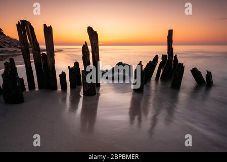 Des piles de bois sur la mer Baltique au coucher du soleil sur le village de Karwia, en Pologne Banque D'Images