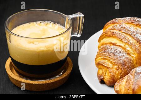 Tasse de café et croissants fraîchement cuits sur une table sombre. Concept petit déjeuner servi. Pâte française à base de pâte feuilletée Banque D'Images