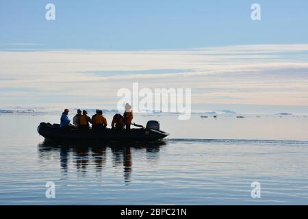 Touristes dans un zodiaque sur un miroir calme jour près d'Alkfjellet dans le détroit de Hinloopen, Svalbard. Banque D'Images