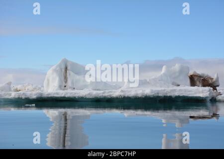 Vue imprenable sur la glace de mer flottante lors d'une journée d'été calme à Svalbard, avec le ciel pastel reflété dans la surface de l'eau. Banque D'Images