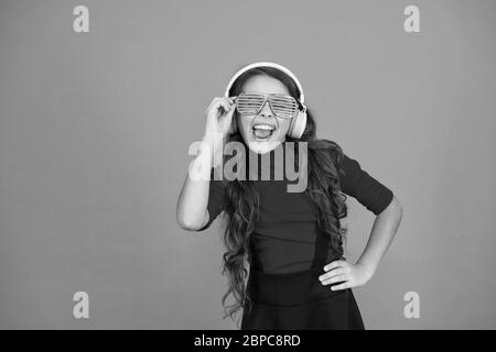 Piste froide. Fille avec lunettes arrière-plan orange. Événement et divertissement. Fille de fête. Accessoire de fête. Amuse-toi bien. Liste de lecture pour la fête. Concept de musique. Enfant porter des lunettes. Magasin de mode de lunettes. Banque D'Images