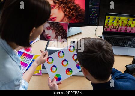 Photographe et graphiste travaillant au bureau avec ordinateur portable, moniteur, tablette de dessin graphique et palette de couleurs. Créer une équipe discutant des idées dans Banque D'Images