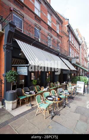 Côte Bistro, vue au niveau de la rue d'un café élégant avec auvent noir et chaises en osier disposées à l'extérieur sur le trottoir, Kensington Banque D'Images