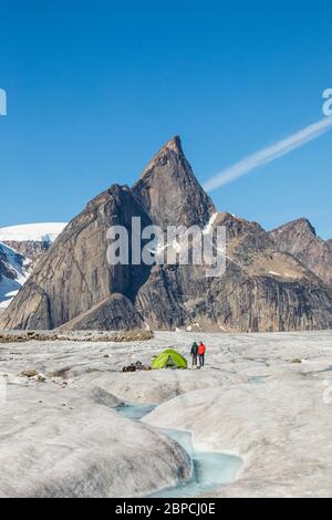 Deux alpinistes se tiennent à côté de la tente sur le glacier sous le sommet de la montagne. Banque D'Images