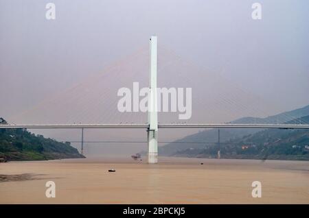 Fengdu, Chongqing, Chine - 8 mai 2010 : fleuve Yangtze. Tour de suspension en béton ou pylône de pont routier suspendu au milieu de l'eau brune sous le lig Banque D'Images