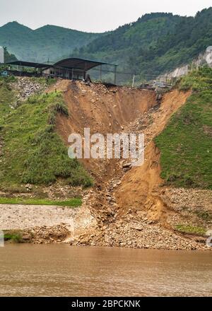 Huangqikou, Chongqing, Chine - 8 mai 2010 : fleuve Yangtze. S'est effondrée la shoreliine avec la terre brune glissement sous les montagnes vertes boisées derrière brun Banque D'Images