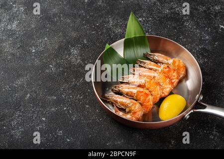 Les crevettes tigrées grillées sont servies dans une poêle avec une tranche de citron. Banque D'Images