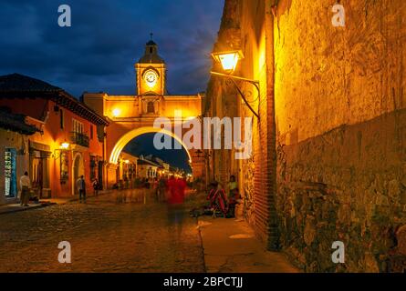 Exposition longue vue de la ville de l'Arc de Santa Catalina la nuit avec un mouvement flou des gens à Antigua, Guatemala. Banque D'Images