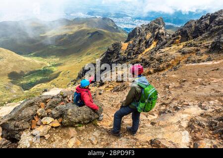 Deux jeunes routards avec casque de protection le long de la randonnée du volcan Rucu Pichincha et avec la vue aérienne sur Quito, Andes, Equateur. Banque D'Images