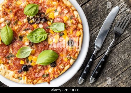 Pizza savoureuse au salami. Pizza avec feuilles de basilic sur l'assiette. Vue de dessus. Banque D'Images