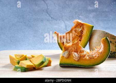 Tranches de citrouille coupées en dés et porridge de citrouille sur un fond en bois sombre. Concept cuisine citrouille hachée. Fond de nourriture. Mise au point sélective. Banque D'Images