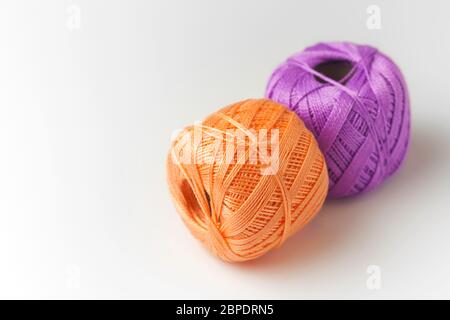 Deux pelées de fil en violet et orange. Tricoter des fils sur fond blanc. Hobby. Banque D'Images