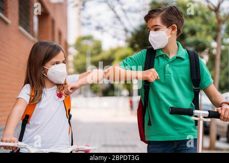 Un garçon et une fille avec un masque saluant dans la rue pendant la pandémie du coronavirus Banque D'Images