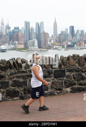 New York, États-Unis. 18 mai 2020. Un enfant portant un masque de visage marche près de Hamilton Park avec Manhattan Skyline en arrière-plan à Weehawken du New Jersey, aux États-Unis, le 18 mai 2020. Le nombre de cas de COVID-19 aux États-Unis a dépassé 1.5 millions lundi, pour atteindre 1,500,753 à 4 h 03 (2003 GMT), selon le Centre for Systems Science and Engineering (CSSE) de l'Université Johns Hopkins. Entre-temps, le nombre de décès au niveau national de COVID-19 a atteint 90,312, selon la CSSE. Crédit : Wang Ying/Xinhua/Alay Live News Banque D'Images