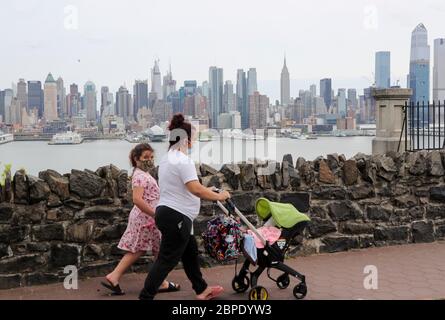 New York, États-Unis. 18 mai 2020. Les personnes portant des masques de visage marchent près de Hamilton Park avec Manhattan Skyline en arrière-plan à Weehawken du New Jersey, les États-Unis, le 18 mai 2020. Le nombre de cas de COVID-19 aux États-Unis a dépassé 1.5 millions lundi, pour atteindre 1,500,753 à 4 h 03 (2003 GMT), selon le Centre for Systems Science and Engineering (CSSE) de l'Université Johns Hopkins. Entre-temps, le nombre de décès au niveau national de COVID-19 a atteint 90,312, selon la CSSE. Crédit : Wang Ying/Xinhua/Alay Live News Banque D'Images