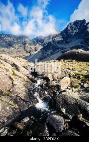 Ruisseau de montagne en chute de la corrie de montagne glaciée de Coire Lagan dans les montagnes Black Cuillin au-delà, île de Skye, Écosse, Royaume-Uni Banque D'Images