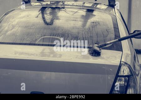 Un homme lave une voiture au lavage de voiture en libre service. Banque D'Images