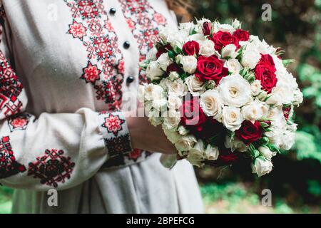 mariage de mariée de tenir à la main bouquet de biège et roses rouges. Banque D'Images