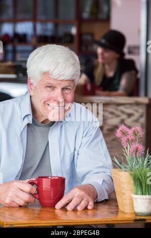 Senior homme assis seul à la table dans un café Banque D'Images