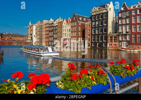 Belle danse typiquement néerlandais maisons et bateaux de touristes au canal à Amsterdam Damrak, journée ensoleillée, Hollande, Pays-Bas. Banque D'Images