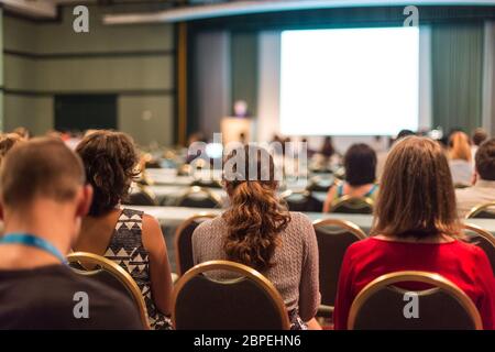 Le président Faire une présentation à une réunion d'affaires. Public dans la salle de conférence. Entreprises et de l'entrepreneuriat. L'accent sur les gens de méconnaissable à l'arrière. Banque D'Images