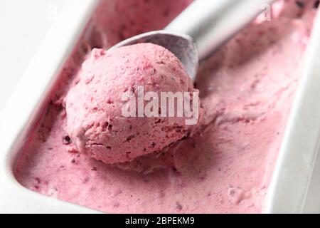 Glace aux baies maison dans un bac métallique avec une cuillère sur fond blanc. Gros plan. Banque D'Images
