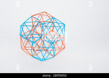 Fait main orange et turquoise modèle tridimensionnel de solides géométriques sur un fond texturé blanc. Banque D'Images
