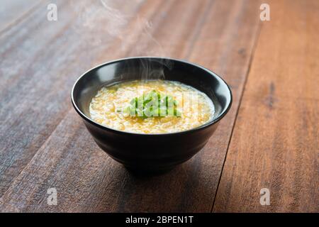 Bol de congee style asiatique sur fond de table en bois. Banque D'Images