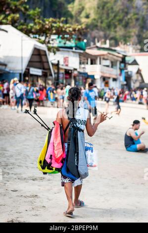 Les vendeurs de plage marchent le long de la plage à El Nido en vendant toutes sortes de choses aux touristes qui partent en excursion d'une journée/bateaux. Banque D'Images