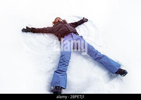 Jeune femme gaie couché sur le livre blanc la neige propre making snow angel, profitant de l'hiver météo, heureux vacances d'hiver Banque D'Images