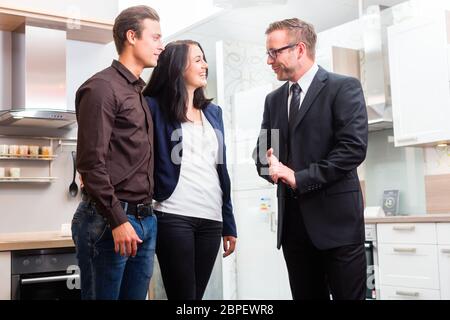 L'homme et de la femme consulter vendeur pour cuisine domestique en studio ou magasin de meubles Banque D'Images