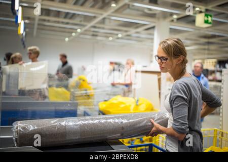 Jolie jeune femme choisir le bon mobilier pour son appartement dans un magasin d'accessoires de maison moderne - avec un chariot, fait du shopping - de payer pour le Banque D'Images