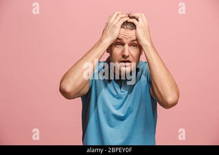 Horrible, stress, choc. Demi-longueur mâle isolée au portrait studio rose. Jeune homme surpris émotionnelle qui serre la tête dans les mains. Les émotions humaines, faci Banque D'Images