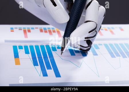 Close-up d'une main robotique en utilisant un stylo tout en travaillant sur le graphique Banque D'Images