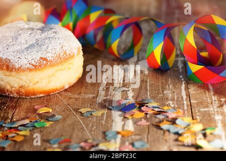 Donut avec décoration de carnaval colorée sur table rustique en bois Banque D'Images